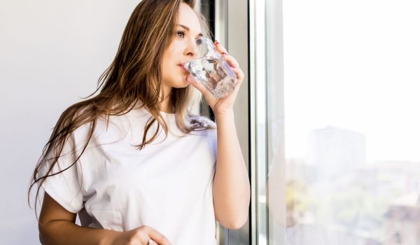 Mujer mirando por la ventana bebiendo agua Atrium Polar Mujer mirando por la ventana bebiendo agua Atrium Polar